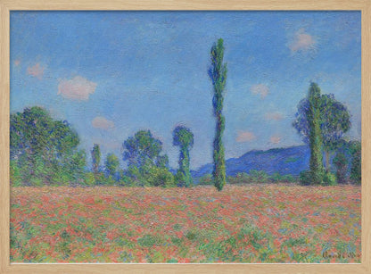 An impressionist painting of a vibrant landscape, 'Poppy Field' by Claude Monet, in a silver frame. It depicts a field of red flowers in the foreground, with a line of green trees and tall poplars against a backdrop of distant blue hills and a bright blue sky with soft clouds. Print
