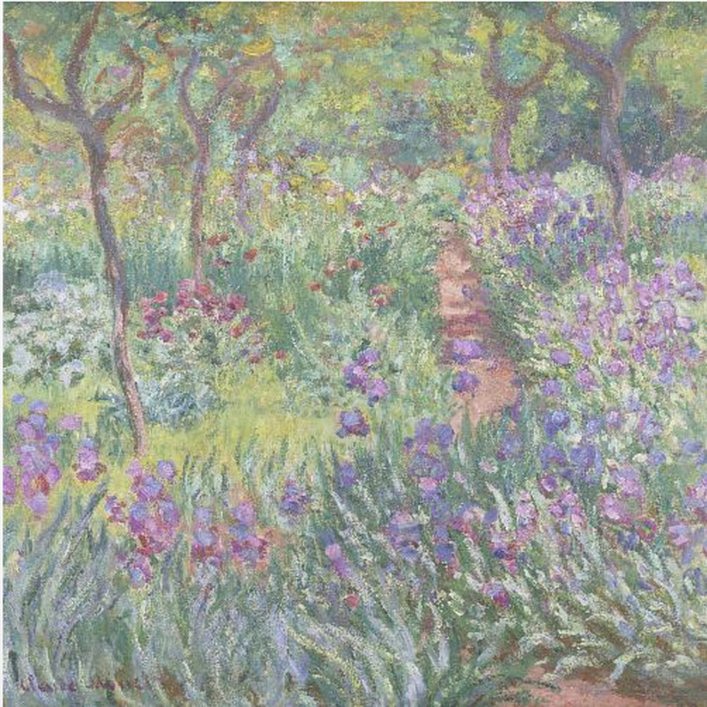 An impressionist painting by Claude Monet, 'The Artist's Garden at Giverny,' set in a light wood frame. The artwork depicts a lush, vibrant garden with a path winding through it. The foreground is dominated by purple irises and tall green leaves, while the background features trees and a mix of colorful flowers in shades of red, yellow, and white, all rendered with visible, textured brushstrokes. Print