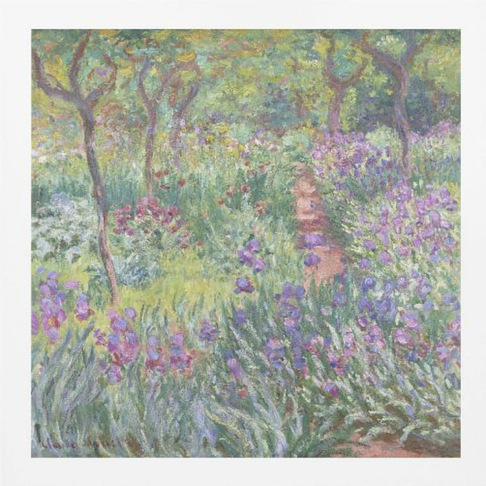 An impressionist painting by Claude Monet, 'The Artist's Garden at Giverny,' set in a light wood frame. The artwork depicts a lush, vibrant garden with a path winding through it. The foreground is dominated by purple irises and tall green leaves, while the background features trees and a mix of colorful flowers in shades of red, yellow, and white, all rendered with visible, textured brushstrokes. Print