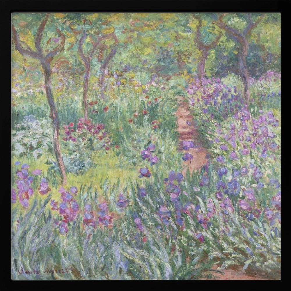 An impressionist painting by Claude Monet, 'The Artist's Garden at Giverny,' set in a light wood frame. The artwork depicts a lush, vibrant garden with a path winding through it. The foreground is dominated by purple irises and tall green leaves, while the background features trees and a mix of colorful flowers in shades of red, yellow, and white, all rendered with visible, textured brushstrokes. Print