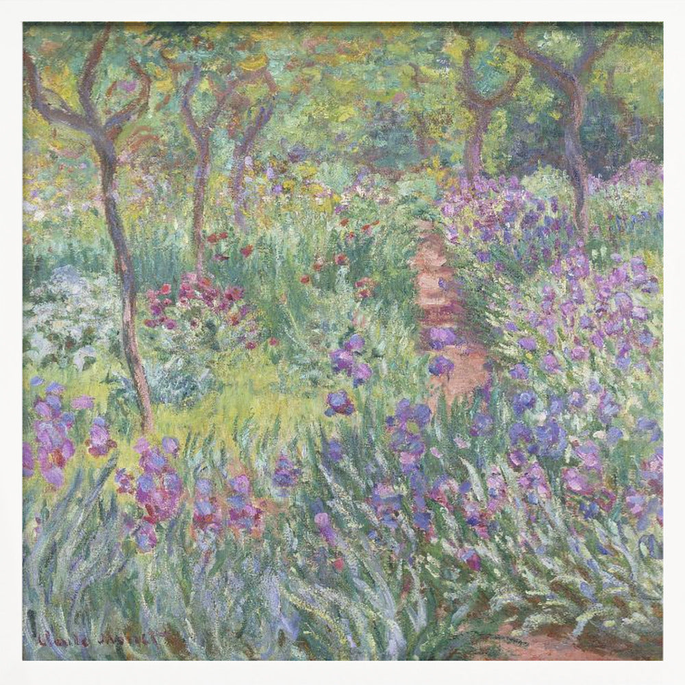 An impressionist painting by Claude Monet, 'The Artist's Garden at Giverny,' set in a light wood frame. The artwork depicts a lush, vibrant garden with a path winding through it. The foreground is dominated by purple irises and tall green leaves, while the background features trees and a mix of colorful flowers in shades of red, yellow, and white, all rendered with visible, textured brushstrokes. Print