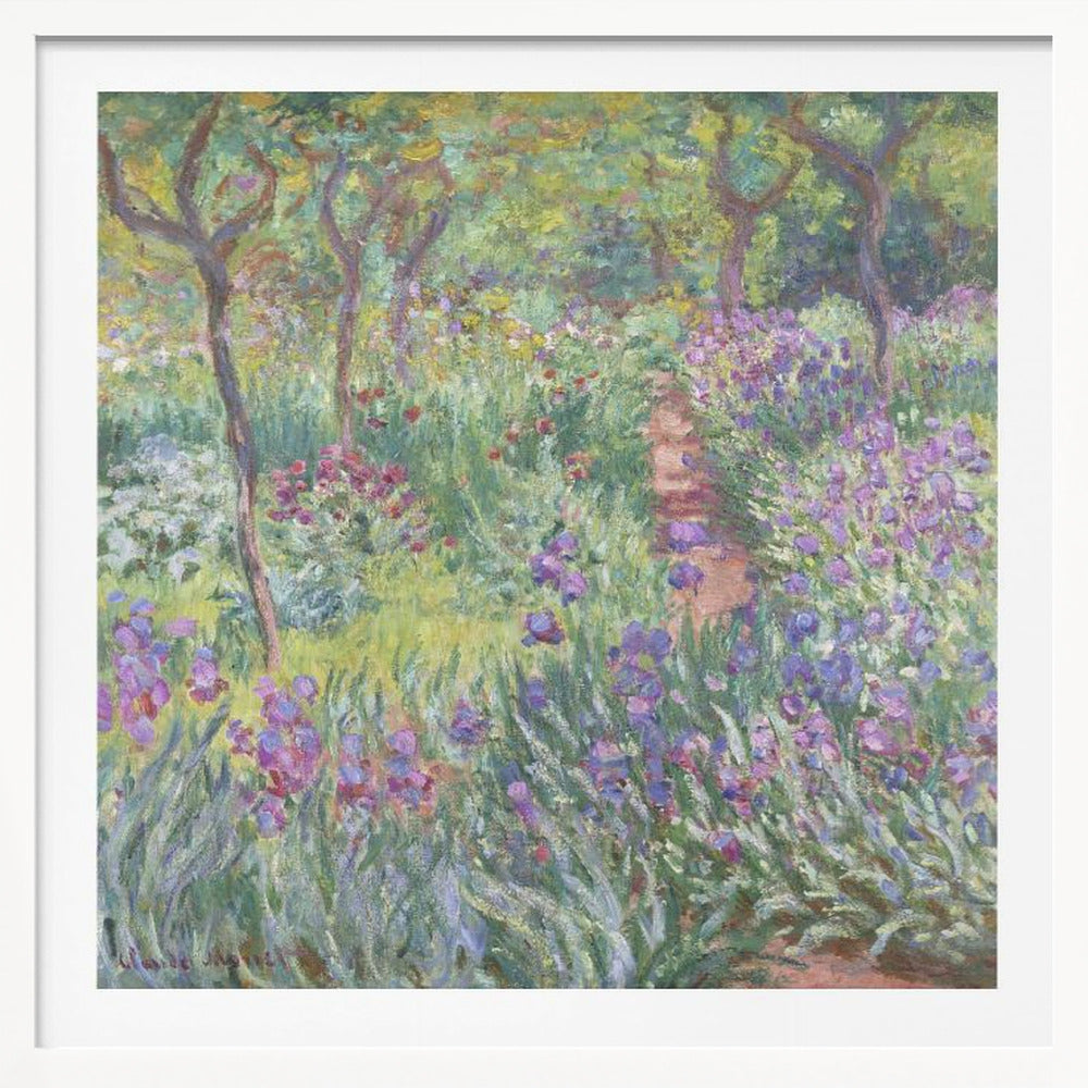 An impressionist painting by Claude Monet, 'The Artist's Garden at Giverny,' set in a light wood frame. The artwork depicts a lush, vibrant garden with a path winding through it. The foreground is dominated by purple irises and tall green leaves, while the background features trees and a mix of colorful flowers in shades of red, yellow, and white, all rendered with visible, textured brushstrokes. Print