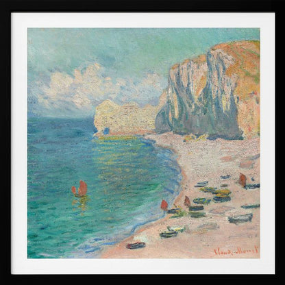 An impressionist painting by Claude Monet depicting the beach at Étretat, France, enclosed in a light wood frame. The artwork shows tall, light-colored cliffs on the right, a sandy beach with small boats, and vibrant turquoise water with a few red-sailed boats. The sky is partly cloudy. Decor