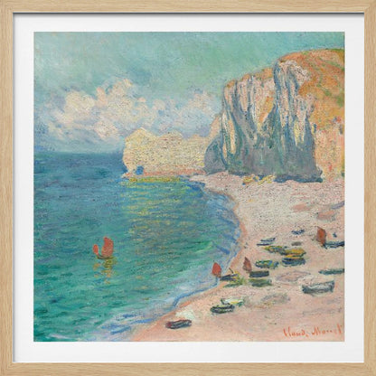 An impressionist painting by Claude Monet depicting the beach at Étretat, France, enclosed in a light wood frame. The artwork shows tall, light-colored cliffs on the right, a sandy beach with small boats, and vibrant turquoise water with a few red-sailed boats. The sky is partly cloudy. Decor