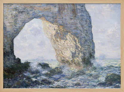An impressionist painting by Claude Monet of the Manneporte rock arch at Étretat, France. Sunlight illuminates the massive stone arch as turbulent blue and white waves crash against the rocky shoreline below. The artwork is displayed in a silver frame. Decor