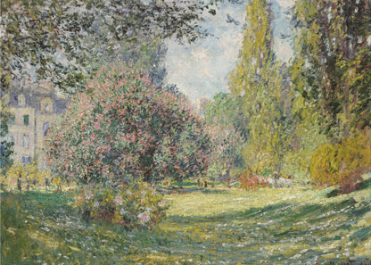 An impressionist painting by Claude Monet titled 'The Parc Monceau' displayed in a silver frame. The scene depicts a sunlit park with lush green grass, a large pink-flowering bush, and tall, leafy trees under a pale blue sky. Decor