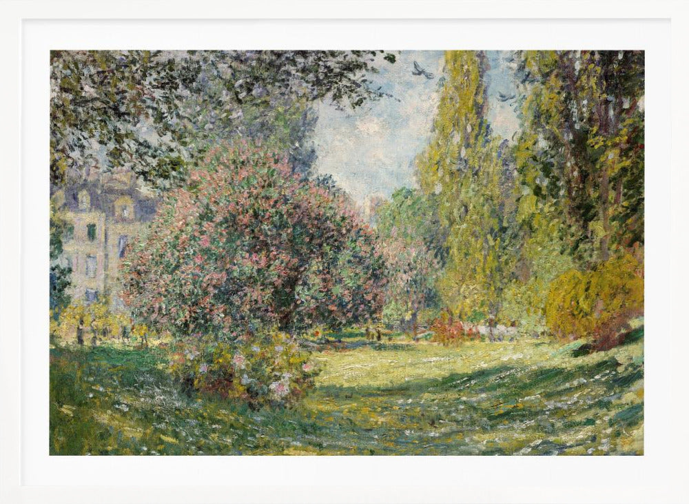 An impressionist painting by Claude Monet titled 'The Parc Monceau' displayed in a silver frame. The scene depicts a sunlit park with lush green grass, a large pink-flowering bush, and tall, leafy trees under a pale blue sky. Decor