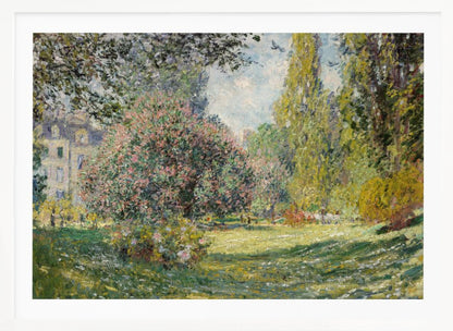 An impressionist painting by Claude Monet titled 'The Parc Monceau' displayed in a silver frame. The scene depicts a sunlit park with lush green grass, a large pink-flowering bush, and tall, leafy trees under a pale blue sky. Decor