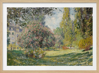 An impressionist painting by Claude Monet titled 'The Parc Monceau' displayed in a silver frame. The scene depicts a sunlit park with lush green grass, a large pink-flowering bush, and tall, leafy trees under a pale blue sky. Decor