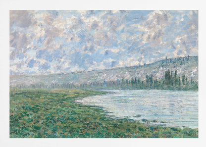 An Impressionist painting by Claude Monet, 'The Seine at Vétheuil', depicting a tranquil landscape. In the foreground, a lush green riverbank meets the calm, reflective water. A distant, soft-focus hillside rises under a vast sky filled with puffy white and grey clouds against a light blue background. The artwork is characterized by visible, textured brushstrokes and is displayed in a modern silver frame. Artwork