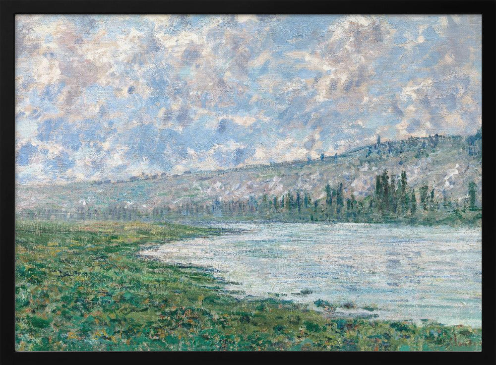 An Impressionist painting by Claude Monet, 'The Seine at Vétheuil', depicting a tranquil landscape. In the foreground, a lush green riverbank meets the calm, reflective water. A distant, soft-focus hillside rises under a vast sky filled with puffy white and grey clouds against a light blue background. The artwork is characterized by visible, textured brushstrokes and is displayed in a modern silver frame. Artwork
