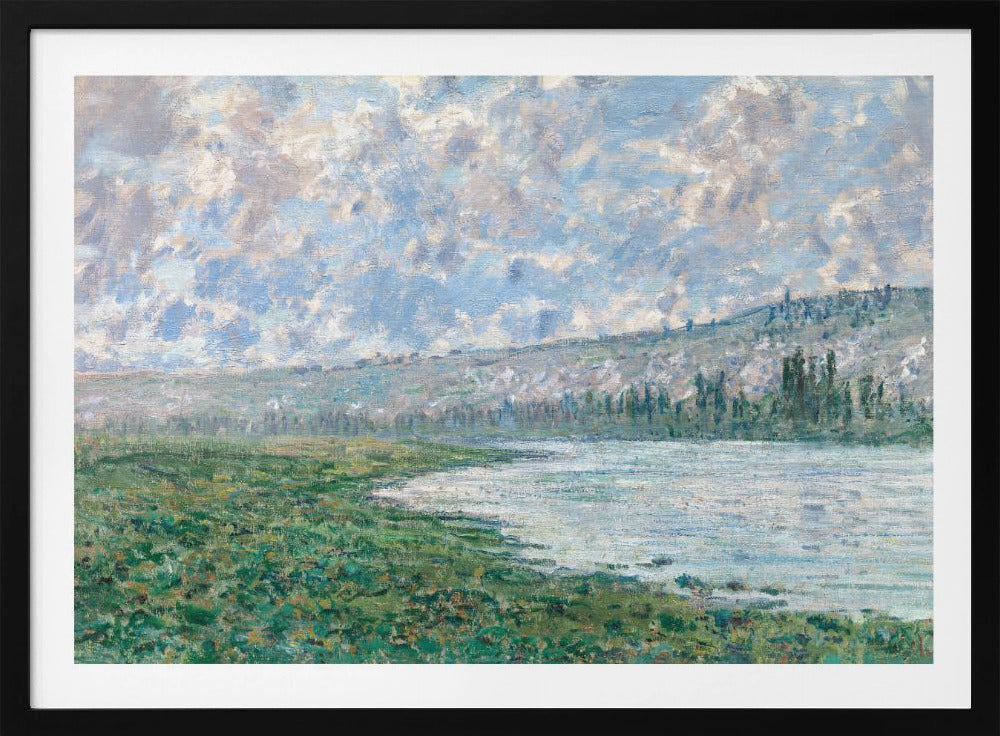An Impressionist painting by Claude Monet, 'The Seine at Vétheuil', depicting a tranquil landscape. In the foreground, a lush green riverbank meets the calm, reflective water. A distant, soft-focus hillside rises under a vast sky filled with puffy white and grey clouds against a light blue background. The artwork is characterized by visible, textured brushstrokes and is displayed in a modern silver frame. Artwork