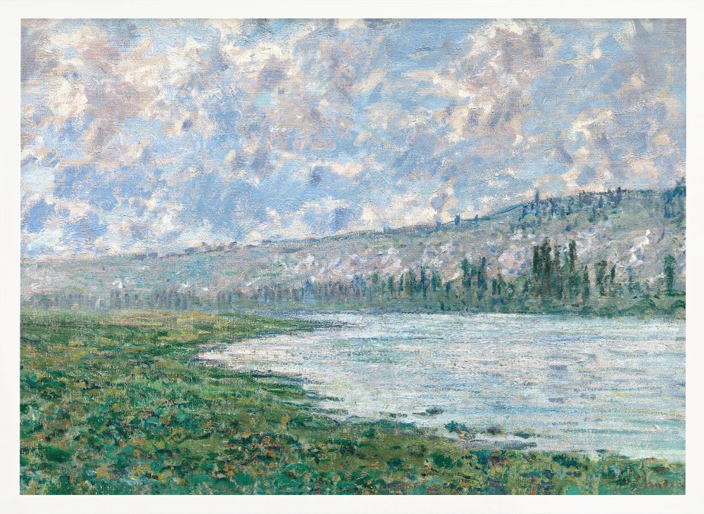 An Impressionist painting by Claude Monet, 'The Seine at Vétheuil', depicting a tranquil landscape. In the foreground, a lush green riverbank meets the calm, reflective water. A distant, soft-focus hillside rises under a vast sky filled with puffy white and grey clouds against a light blue background. The artwork is characterized by visible, textured brushstrokes and is displayed in a modern silver frame. Artwork