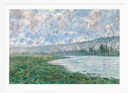 An Impressionist painting by Claude Monet, 'The Seine at Vétheuil', depicting a tranquil landscape. In the foreground, a lush green riverbank meets the calm, reflective water. A distant, soft-focus hillside rises under a vast sky filled with puffy white and grey clouds against a light blue background. The artwork is characterized by visible, textured brushstrokes and is displayed in a modern silver frame. Artwork