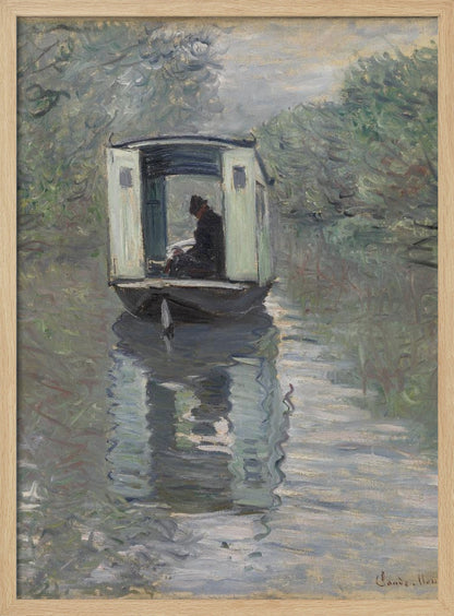 An Impressionist painting by Claude Monet titled 'The Studio Boat,' depicting a figure in a hat and dark coat sitting inside a small, white-paneled boat on a calm, grey-green river. The scene is enveloped in a soft, hazy light, with blurry trees lining the banks and a strong, rippling reflection of the boat in the water. Artwork
