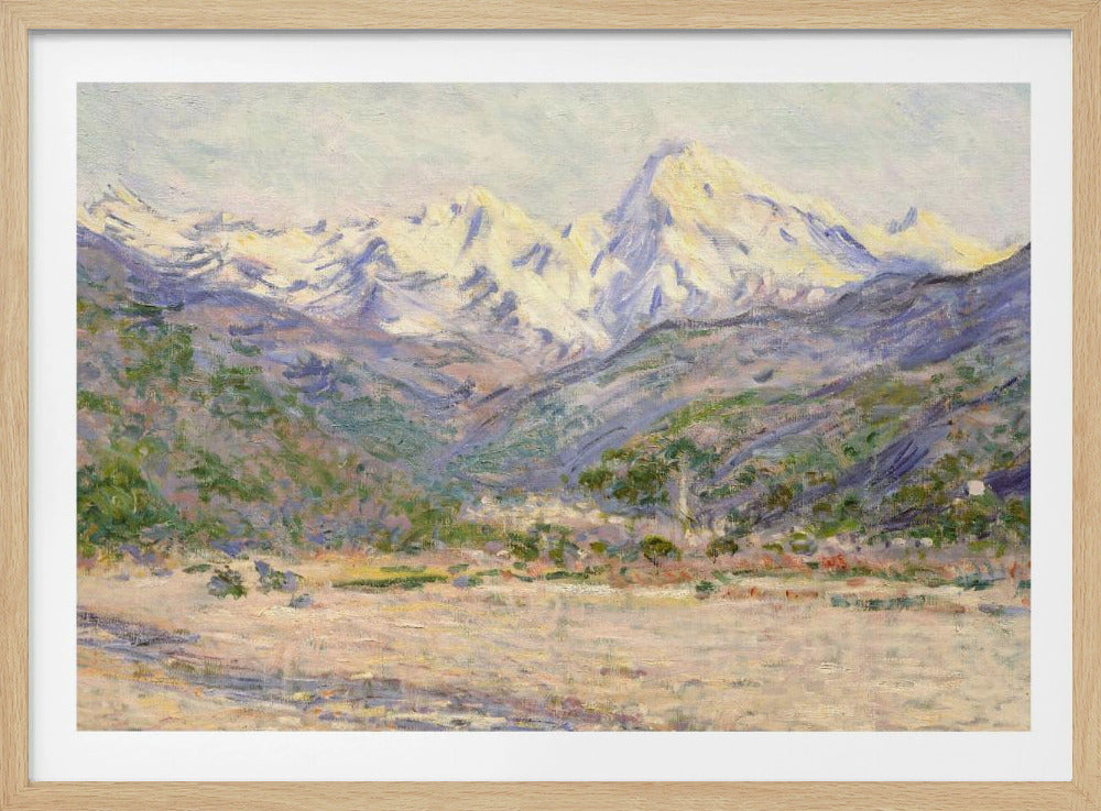 An impressionistic painting of a vast mountain range. The snow-covered peaks are bathed in pale yellow sunlight, while the lower slopes are cast in shades of purple and blue. A wide, beige valley with patches of green foliage sits in the foreground, all rendered with visible, textured brushstrokes and displayed in a silver frame. Print