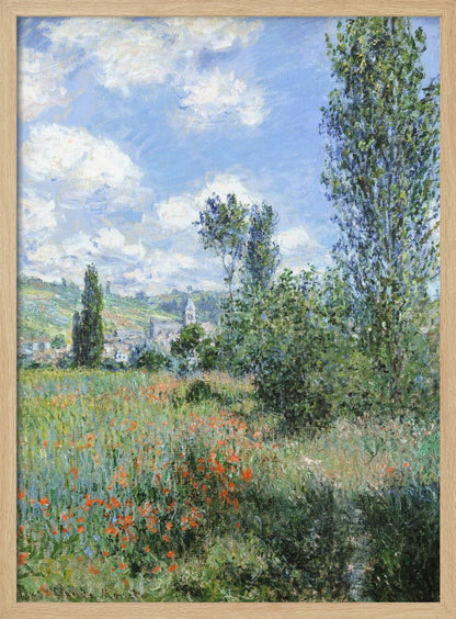 An impressionist painting depicting a vibrant green field filled with red poppies under a bright blue sky with fluffy white clouds. Tall green trees stand on the right, and in the distance, a small village with a church steeple is nestled in the rolling hills. Decor