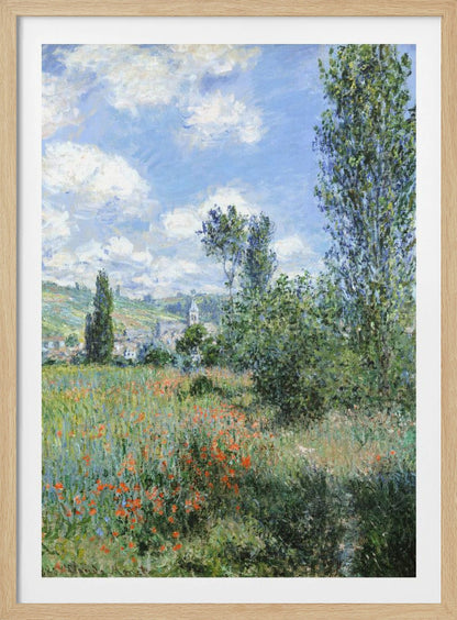 An impressionist painting depicting a vibrant green field filled with red poppies under a bright blue sky with fluffy white clouds. Tall green trees stand on the right, and in the distance, a small village with a church steeple is nestled in the rolling hills. Decor