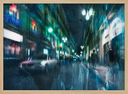 An abstract, moody artwork of a busy city street at night, viewed as if through a rainy window or with motion blur. The scene is dominated by shades of deep blue and vibrant green, with glowing streetlights and neon signs casting reflections on the wet pavement. Silhouettes of people walk down the street, and a car is partially visible on the left. The entire composition has a dynamic, dreamlike quality and is presented in a silver frame. Poster
