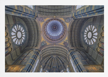 An upward-looking view of the highly ornate vaulted ceiling of a grand cathedral, featuring a central glass dome, large rose windows, and intricate gold and blue details, all framed in silver. Poster