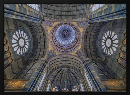 An upward-looking view of the highly ornate vaulted ceiling of a grand cathedral, featuring a central glass dome, large rose windows, and intricate gold and blue details, all framed in silver. Poster