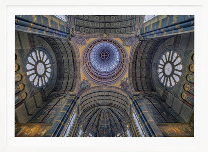 An upward-looking view of the highly ornate vaulted ceiling of a grand cathedral, featuring a central glass dome, large rose windows, and intricate gold and blue details, all framed in silver. Poster