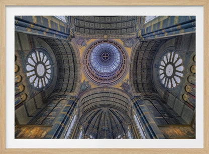 An upward-looking view of the highly ornate vaulted ceiling of a grand cathedral, featuring a central glass dome, large rose windows, and intricate gold and blue details, all framed in silver. Poster