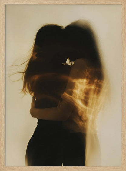 An artistic, long-exposure photograph of two silhouetted figures embracing. Their forms are blurred with motion, and streaks of warm, golden light wash over them against a soft, off-white background, creating a dreamy and intimate mood. Decor