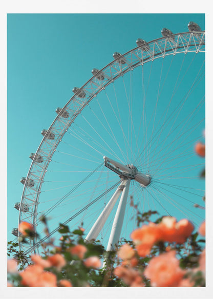 A low-angle shot of the London Eye ferris wheel against a clear, vibrant teal sky. In the foreground, out-of-focus orange flowers create a soft, colorful frame. Poster