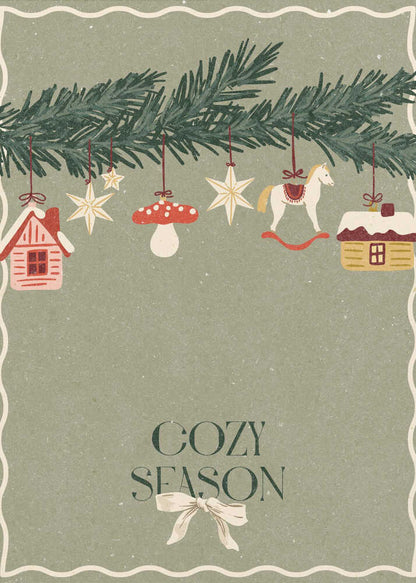 A vintage-style holiday poster with a sage green background. A pine branch hangs at the top, decorated with illustrated ornaments including houses, stars, a mushroom, and a rocking horse. Below, the text 'COZY SEASON' is written in a dark serif font with a light-colored bow underneath. Artwork