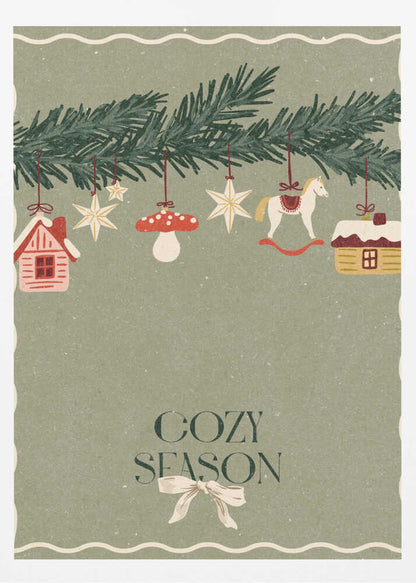 A vintage-style holiday poster with a sage green background. A pine branch hangs at the top, decorated with illustrated ornaments including houses, stars, a mushroom, and a rocking horse. Below, the text 'COZY SEASON' is written in a dark serif font with a light-colored bow underneath. Artwork