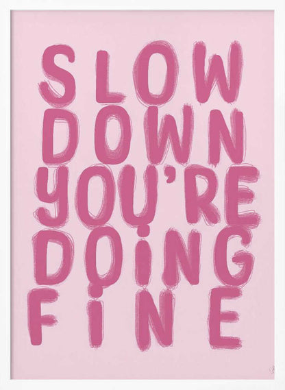 A framed art print featuring the phrase 'SLOW DOWN YOU'RE DOING FINE' in a bold, dark pink, brush-stroke font. The words are stacked vertically against a light pink background, all enclosed within a simple black frame. Artwork