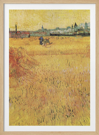 A Post-Impressionist painting by Vincent van Gogh depicting a vast, golden wheat field under a yellow sky. Two figures are harvesting wheat in the middle distance, with a town and industrial buildings on the horizon. The artwork is characterized by thick, textured brushstrokes and is displayed in a black frame. Print