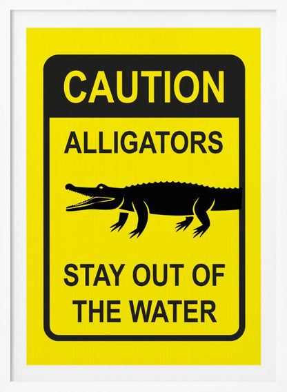 A yellow and black rectangular warning sign in a black frame. The sign reads 'CAUTION ALLIGATORS' at the top, features a black silhouette of an alligator in the center, and says 'STAY OUT OF THE WATER' at the bottom. Decor
