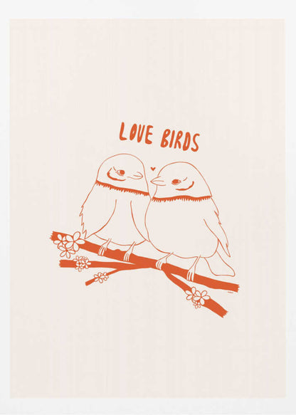 A framed art print featuring a minimalist, reddish-orange illustration on a cream background. Two cartoonish, plump birds sit close together on a flowering branch, looking at each other affectionately. Above them, the text 'LOVE BIRDS' is written in a playful, rounded font. Decor