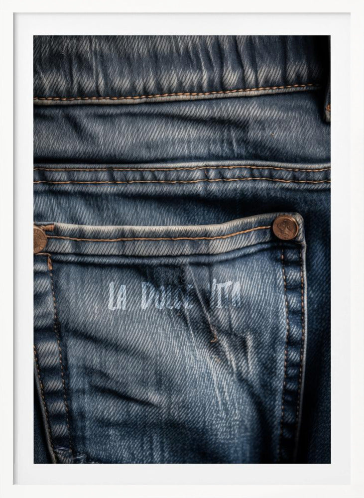 A detailed close-up photograph of a faded blue jean back pocket, showing the texture of the denim, orange stitching, and a copper rivet. Faint white text is stenciled onto the pocket. Poster