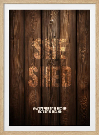 A rustic poster with a dark brown wood panel background. The words 'SHE SHED' are in large, blocky letters with a distressed wood texture. Below, a smaller caption reads 'WHAT HAPPENS IN THE SHE SHED STAYS IN THE SHE SHED'. The poster is displayed in a thin black frame. Print