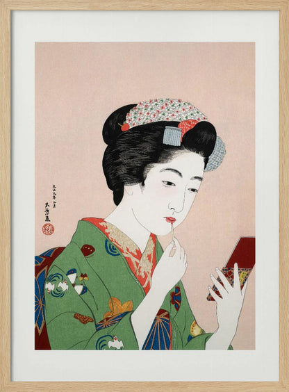 A Japanese ukiyo-e woodblock print of a woman in a green kimono applying red lipstick while looking into a small handheld mirror. Her black hair is elaborately styled, and the background is a soft pink. Artwork