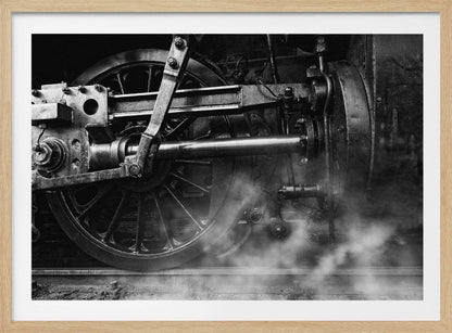 A dramatic, black and white close-up photograph of the wheels and driving rods of a steam locomotive. Puffs of steam rise from the tracks, partially obscuring the lower part of the machinery. Print