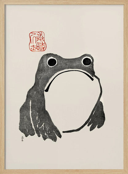 A minimalist Japanese-style ink wash painting of a stylized frog with a grumpy expression. The frog is rendered in black ink on a cream-colored paper, with a large white throat pouch. A red artist's seal is stamped above the frog's head. The artwork is presented in a simple black frame. Artwork
