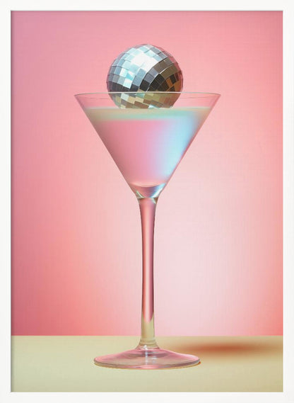 A sleek martini glass filled with an iridescent pink and blue cocktail is centered against a solid pink background. A small, shiny silver disco ball rests on the rim of the glass, completing the festive and stylish composition. Decor