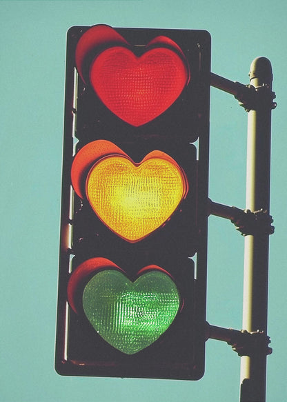 A vertical traffic light against a solid teal sky, with its red, yellow, and green signals all shaped like glowing hearts. Wall Art