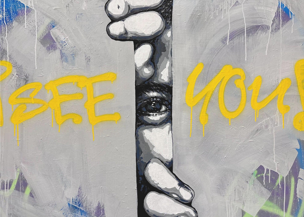A framed modern art piece depicting a black and white eye peeking through a narrow vertical opening, with hands gripping the sides. The background is a textured gray with vibrant yellow graffiti-style text that reads 'I SEE YOU!' with paint drips. Print