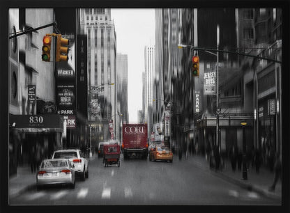 A framed, stylized photograph of a busy New York City street, presented mostly in black and white with a motion blur effect. Pops of color highlight red vehicles and yellow traffic lights, drawing focus down the urban canyon lined with skyscrapers and Broadway signs. Decor