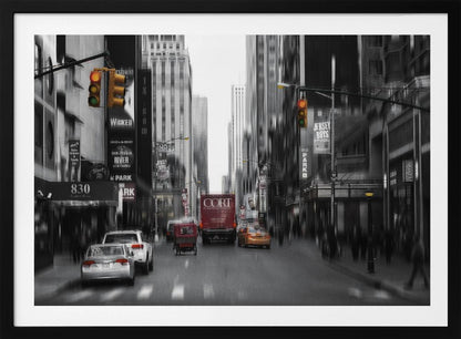 A framed, stylized photograph of a busy New York City street, presented mostly in black and white with a motion blur effect. Pops of color highlight red vehicles and yellow traffic lights, drawing focus down the urban canyon lined with skyscrapers and Broadway signs. Decor