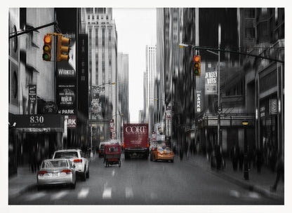 A framed, stylized photograph of a busy New York City street, presented mostly in black and white with a motion blur effect. Pops of color highlight red vehicles and yellow traffic lights, drawing focus down the urban canyon lined with skyscrapers and Broadway signs. Decor