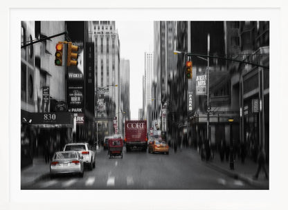 A framed, stylized photograph of a busy New York City street, presented mostly in black and white with a motion blur effect. Pops of color highlight red vehicles and yellow traffic lights, drawing focus down the urban canyon lined with skyscrapers and Broadway signs. Decor