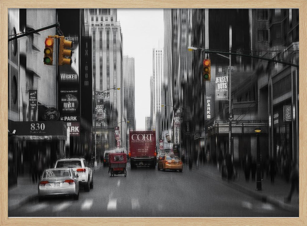 A framed, stylized photograph of a busy New York City street, presented mostly in black and white with a motion blur effect. Pops of color highlight red vehicles and yellow traffic lights, drawing focus down the urban canyon lined with skyscrapers and Broadway signs. Decor