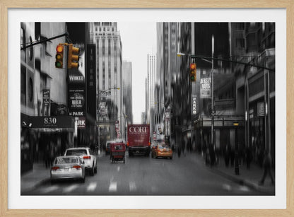 A framed, stylized photograph of a busy New York City street, presented mostly in black and white with a motion blur effect. Pops of color highlight red vehicles and yellow traffic lights, drawing focus down the urban canyon lined with skyscrapers and Broadway signs. Decor