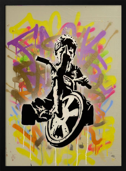 A framed street art piece featuring a black and white stencil of a rebellious child on a tricycle giving the middle finger, set against a vibrant, multi-colored graffiti background with paint drips. Artwork